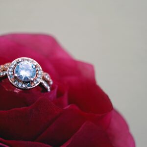 A close-up shot of a sparkling diamond engagement ring nestled in a vibrant red rose, symbolizing love and romance.