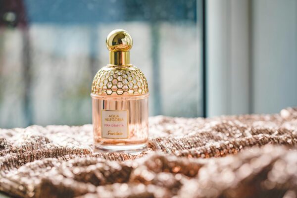 Elegant Guerlain perfume bottle on a textured fabric with natural lighting, exuding luxury and fragrance.