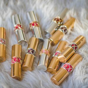 A collection of gold and silver lipstick tubes displayed on a fluffy white fur surface.