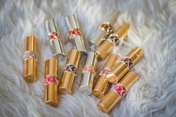 A collection of gold and silver lipstick tubes displayed on a fluffy white fur surface.